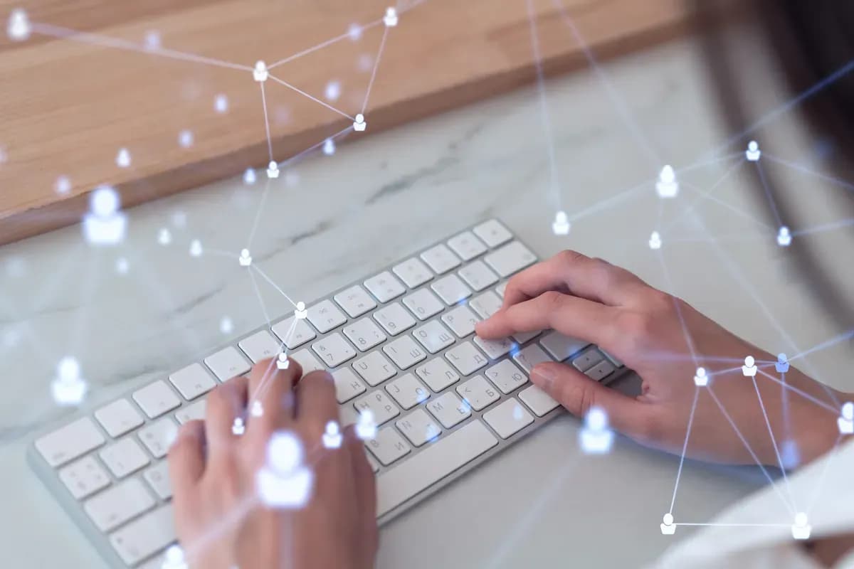 Mains sur un clavier, reliées par un réseau de liens entre des sites